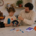 Father and child building a LinkKit astronaut small case textile kit in the kitchen