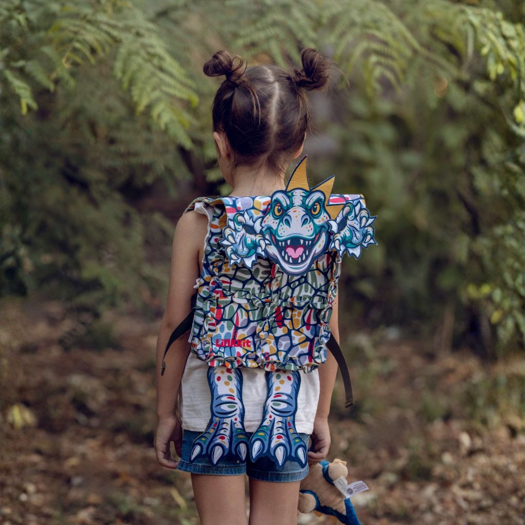 Child wearing a LinkKit T-rex yellow small backpack textile kit from the back