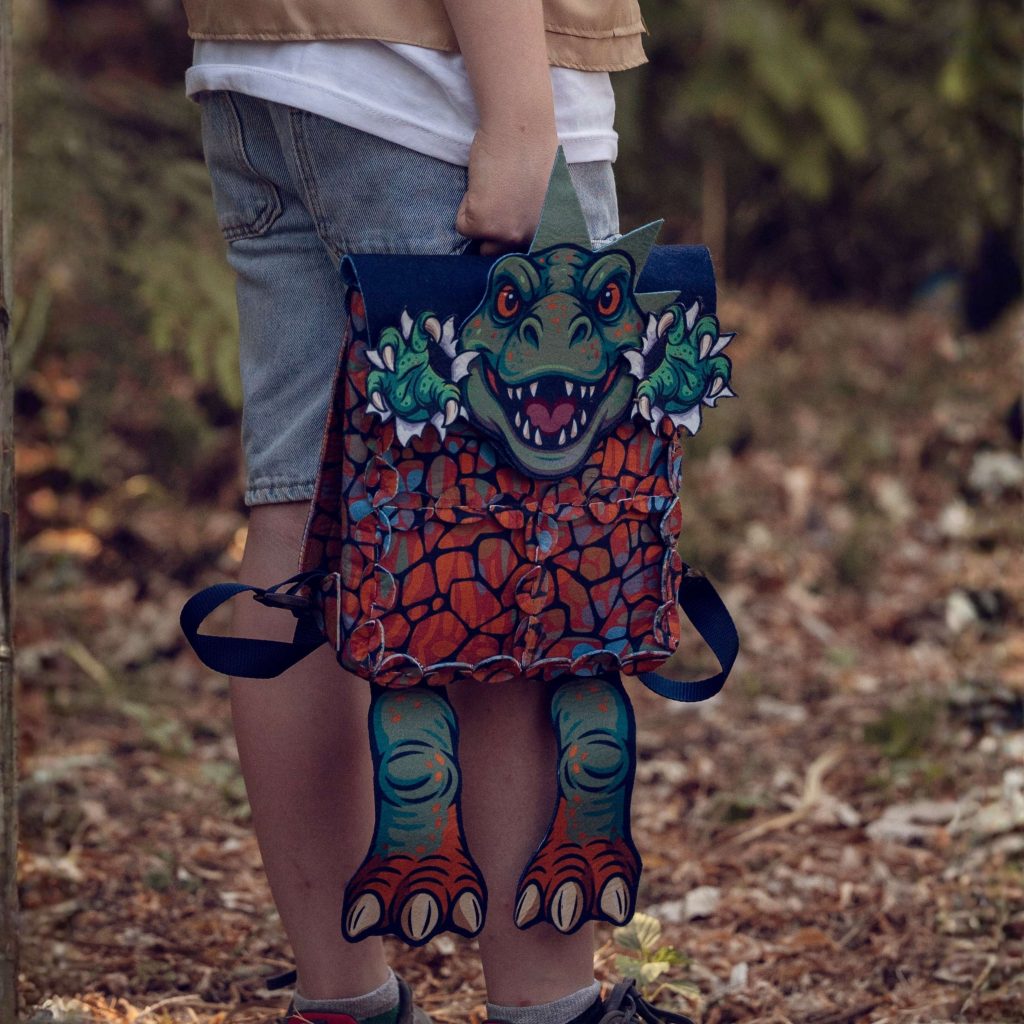 Child wearing a LinkKit T-rex orange small backpack textile kit outdoors
